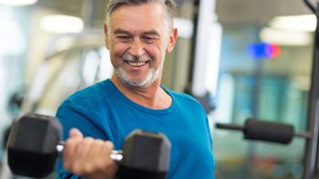 Man enjoying the gym smiling and holding dumbbell e1665981207736 8 Proven Techniques To Actually Enjoy The Gym