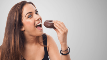 woman snacking on donut 4 Effective Strategies To Combat Snacking Temptations