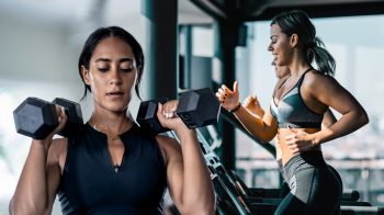 women doing strength training whilst another lady is doing cardio on a treadmill in the background